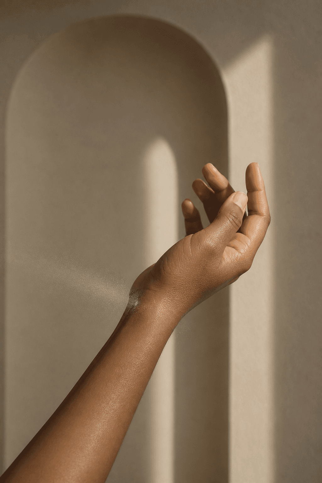 A hand applying perfume at the wrist in warm light
